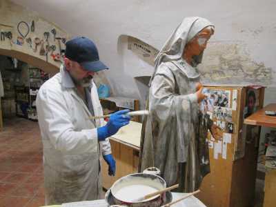 In fondo ci attende il cuore pulsante del luogo: il laboratorio, dove troviamo Claudio Riso con indosso un camice bianco, un capellino azzurro e dei guanti in lattice intento a terminare una statua della Madonna